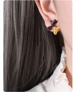 Primer plano de aretes de perro globo en marrón y dorado usados por una modelo