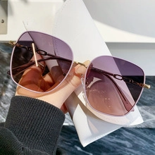 Close-up of oversized gradient purple sunglasses with detailed gold chain-link arms