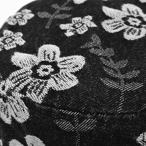 Macro shot of embroidered white flower patterns on black denim bucket hat fabric