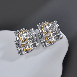 Detailed macro view of irregular wavy metal earrings with hammer texture and gold accents