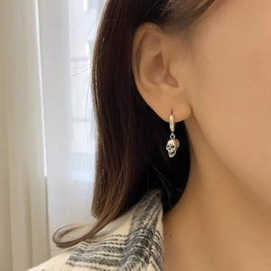 Retro punk style silver skull earrings for men and women shown on a model ear