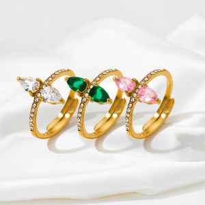 Detailed close-up of three pear-cut zircon rings in emerald, pink and white on silk