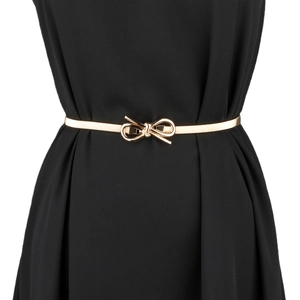 Close-up of golden metal spring belt with a decorative bow buckle on black fabric