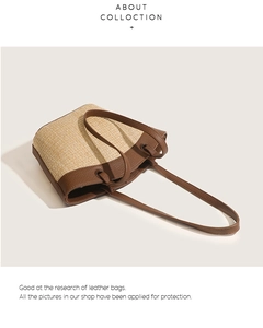 Detail of woven straw tote bag with brown leather trim and knotted shoulder strap