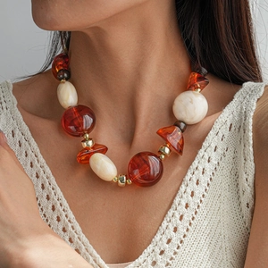 Gros plan sur le collier vintage en perles acryliques ambrées et blanc cassé géométriques