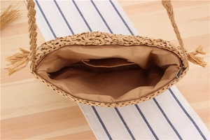 Detail view of woven straw bag interior with lining, zipper closure and fringe strap