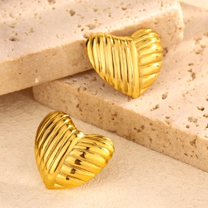 Detail of golden heart earrings with textured stripes on travertine stone display