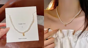 Detail of elegant white pearl necklace featuring a polished gold ball pendant on a neck
