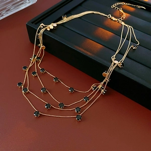 Détail du collier doré multi-rangs avec perles noires, fermoir mousqueton et chaînette