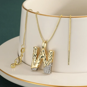 Macro shot of gold-plated letter W pendant with cubic zirconia on a ceramic cup