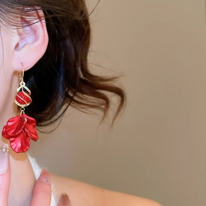 Detail of elegant red petal earrings with gold tassels on a model for a chic look