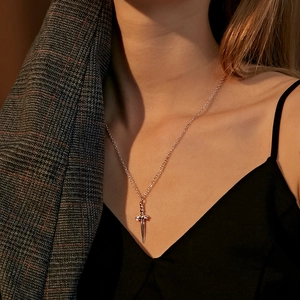 Macro di una collana con ciondolo a spada dorata indossata con dettagli di lusso