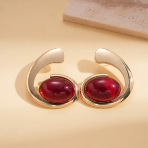 Detail view of gold irregular oval earrings with deep red resin gemstones for women