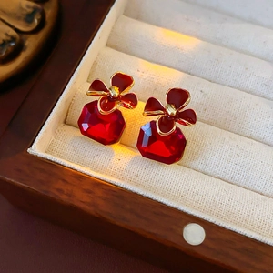 Close-up of vintage red floral earrings with gold edges and faceted gemstones