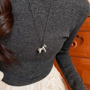 Gros plan du collier pendentif poney argenté mignon avec cordon noir minimaliste sur modèle