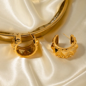 Macro detail of 18k gold plated stainless steel C-shaped stud earrings with rivet texture