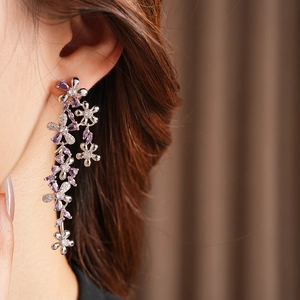 Detail of silver flower tassel earring with purple crystals worn by a model