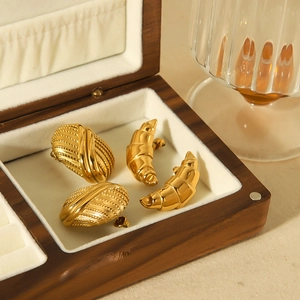 Détail de boucles d'oreilles croissant dorées 18k dans un écrin en bois chic
