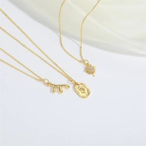 Three gold minimalist necklaces featuring starburst, floral medal, and abstract branch pendants