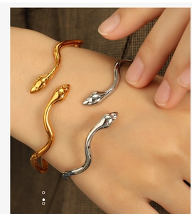 Detail of snake-shaped open bracelets in gold and silver with white zircon snake eyes