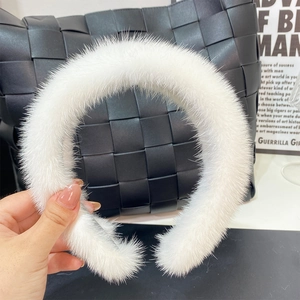 Close-up of fluffy white faux fur headband featuring soft plush texture on black bag