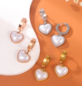 Detailed view of heart-shaped pearl earrings in rose gold, silver and gold titanium steel