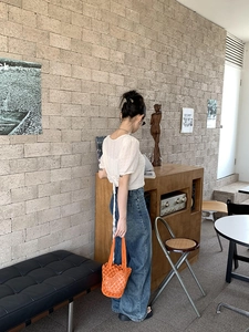 Detail view of a stylish orange woven bucket bag styled with a retro outfit in a cafe