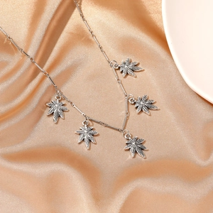 Silver alloy necklace with five maple leaf pendants on champagne silk background