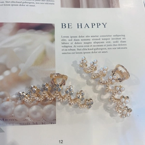 Elegant gold metal hair claw set with pearls and rhinestones on a magazine background