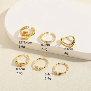 Set of six gold adjustable rings with pentagram stars and zircon stones on a beige surface
