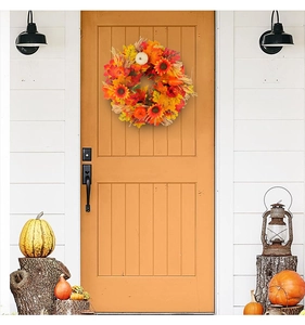 Outdoor decor featuring autumn wreath with maple leaves and pumpkins on orange door