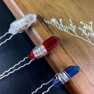 Close-up of three handmade crystal U-shaped hair pins in white, red, and blue colors