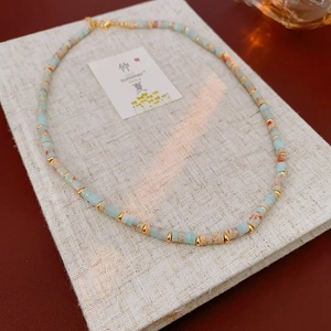 Detail of bohemian beaded necklace with blue stones and gold spacers on linen book