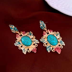 Detailed view of vintage gold earrings with green turquoise and red enamel on red velvet