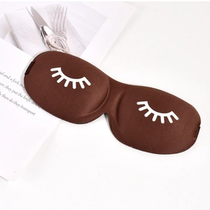 Detail of dark brown 3D sleep mask with white eyelash pattern on a vintage magazine