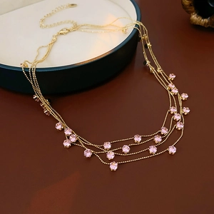 Vue détaillée du collier multicouche en or avec zircons ronds roses sur un plateau