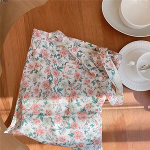 Détail d'un sac cabas en toile à fleurs roses posé sur une table en bois rustique
