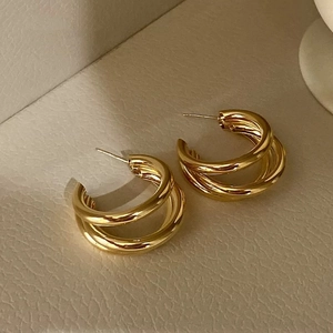Chic triple-layer gold-plated C-shaped hoop earrings for women on cream leather