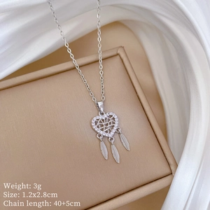 Dettaglio della collana acchiappasogni argento con piume su scatola beige e seta