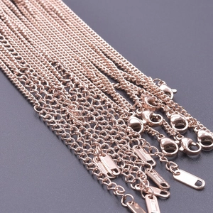 Macro detail of 18k rose gold stainless steel chains with lobster clasps and engravings