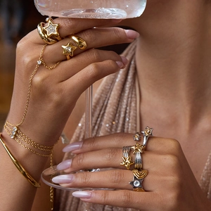 Gros plan de bagues et chaîne de main étoile dorées et argentées avec strass sur un mannequin
