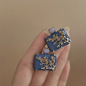 Macro shot of vintage rectangular earrings with dark blue enamel and golden plum blossom