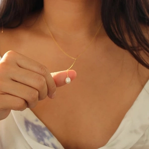Close-up of elegant gold S925 silver Y-shaped necklace with white pearl on woman neck