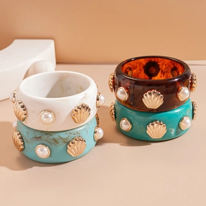 Detail of chunky resin bangles with gold scallops and faux pearls in four assorted colors
