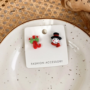 Detail of asymmetrical Christmas earrings with snowman and candy cane on ceramic tray