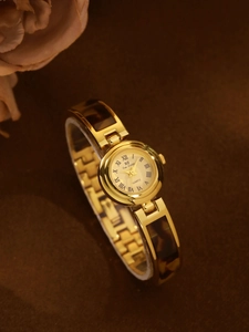 Close-up of tortoise shell pattern inlay on gold-plated quartz watch bracelet strap