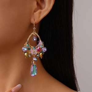 Close-up of gold dangle earrings with colorful floral crystals and iridescent teardrop beads