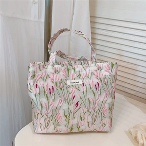 Detailed view of pink floral jacquard fabric and simple wish label on small tote bag