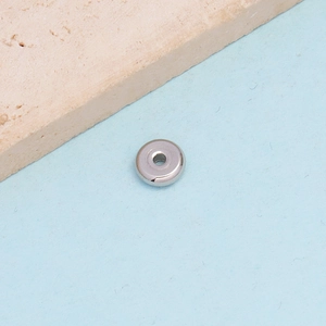 Close-up of a polished silver stainless steel flat disc spacer bead with a center hole