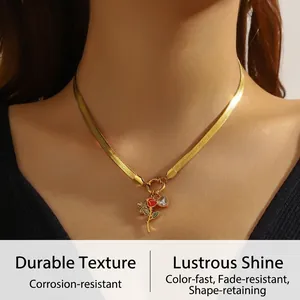 Détail de la chaîne serpent dorée avec rose en émail rouge et pendentif cœur en cristal